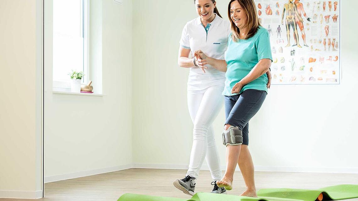 Patientin mit Beinmanschette läuft mit Physiotherapeutin über unebenen Untergrund, Bild: ottobock