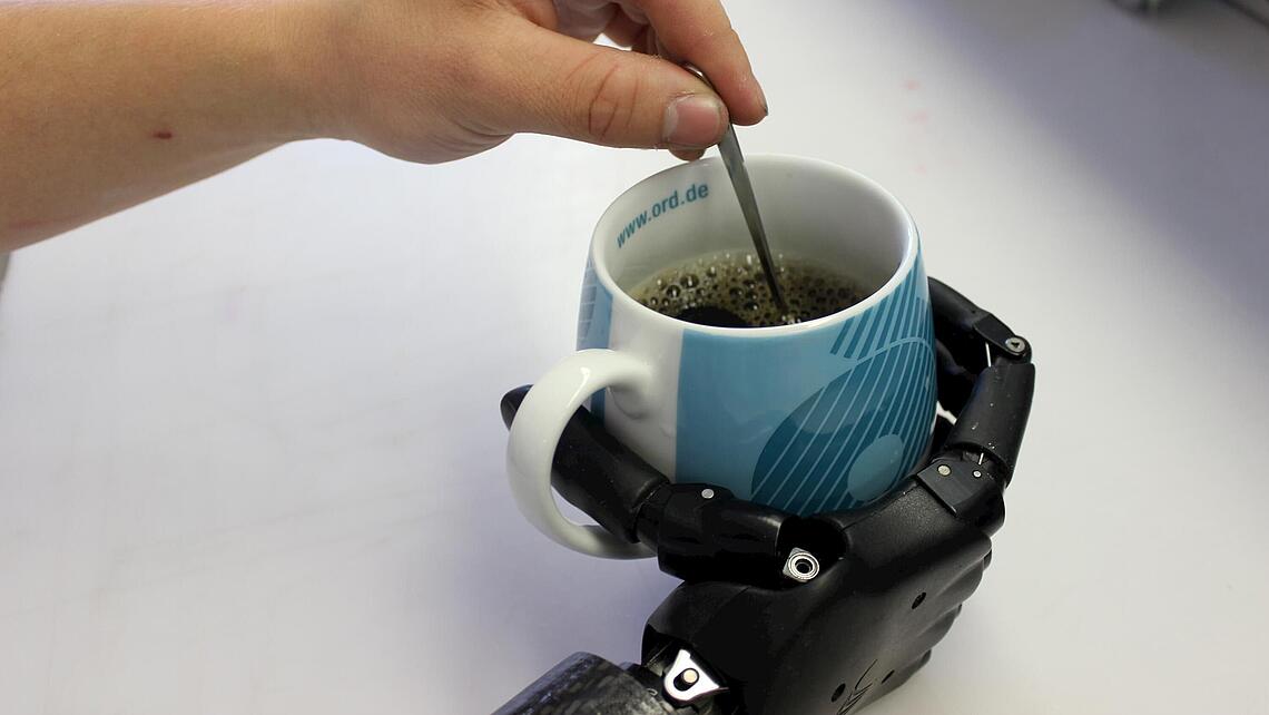 Unterarmprothese mit Hand, die eine Kaffetasse hält