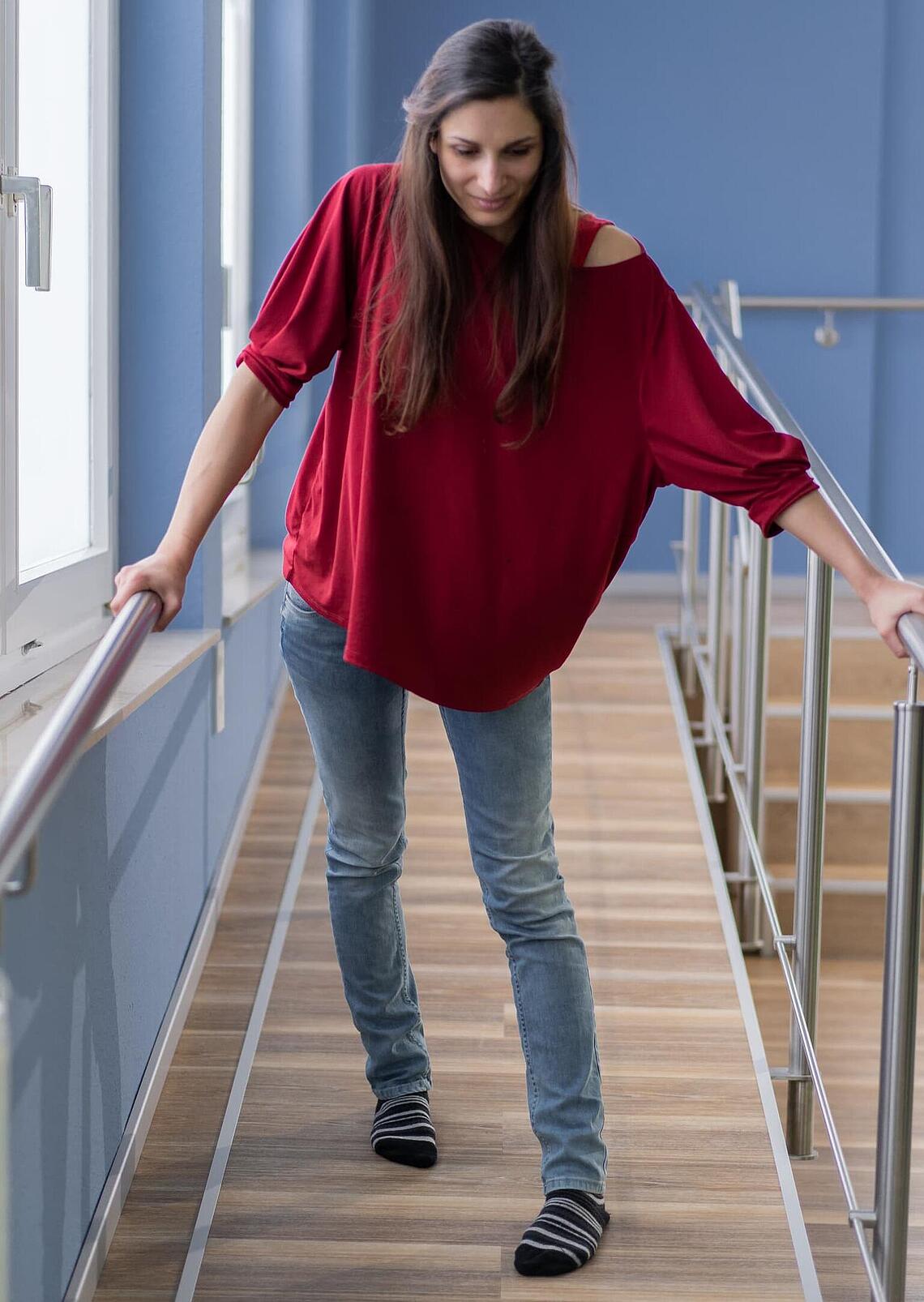 Frau mit Spastik läuft Rampe runter, © Ottobock Frau läuft ohne EXOPULSE Mollii Suit eine Rampe mühevoll runter, © Ottobock