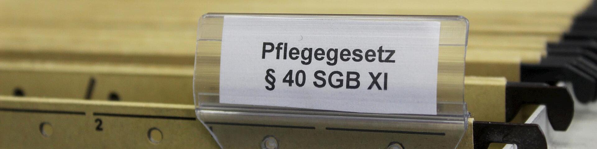 Pflegegesetz-Aktenordner Halterung mit Aktenordnern, bei dem einer mit dem Pflegegesetz beschriftet ist