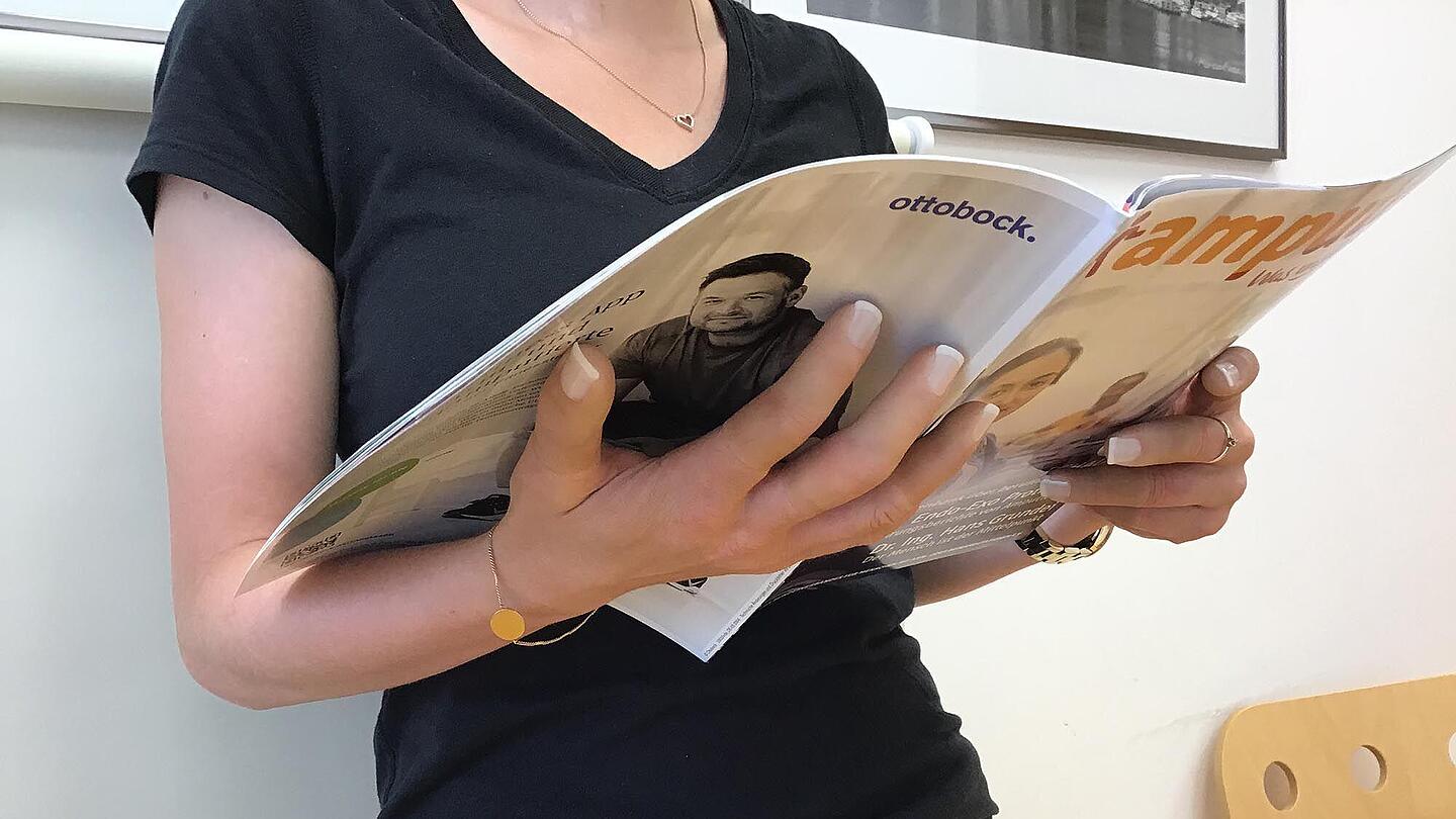 Silikon-Fingerprothesen an der Hand einer Frau die Zeitung liest  Silikon-Fingerprothesen an Frau die Zeitung liest