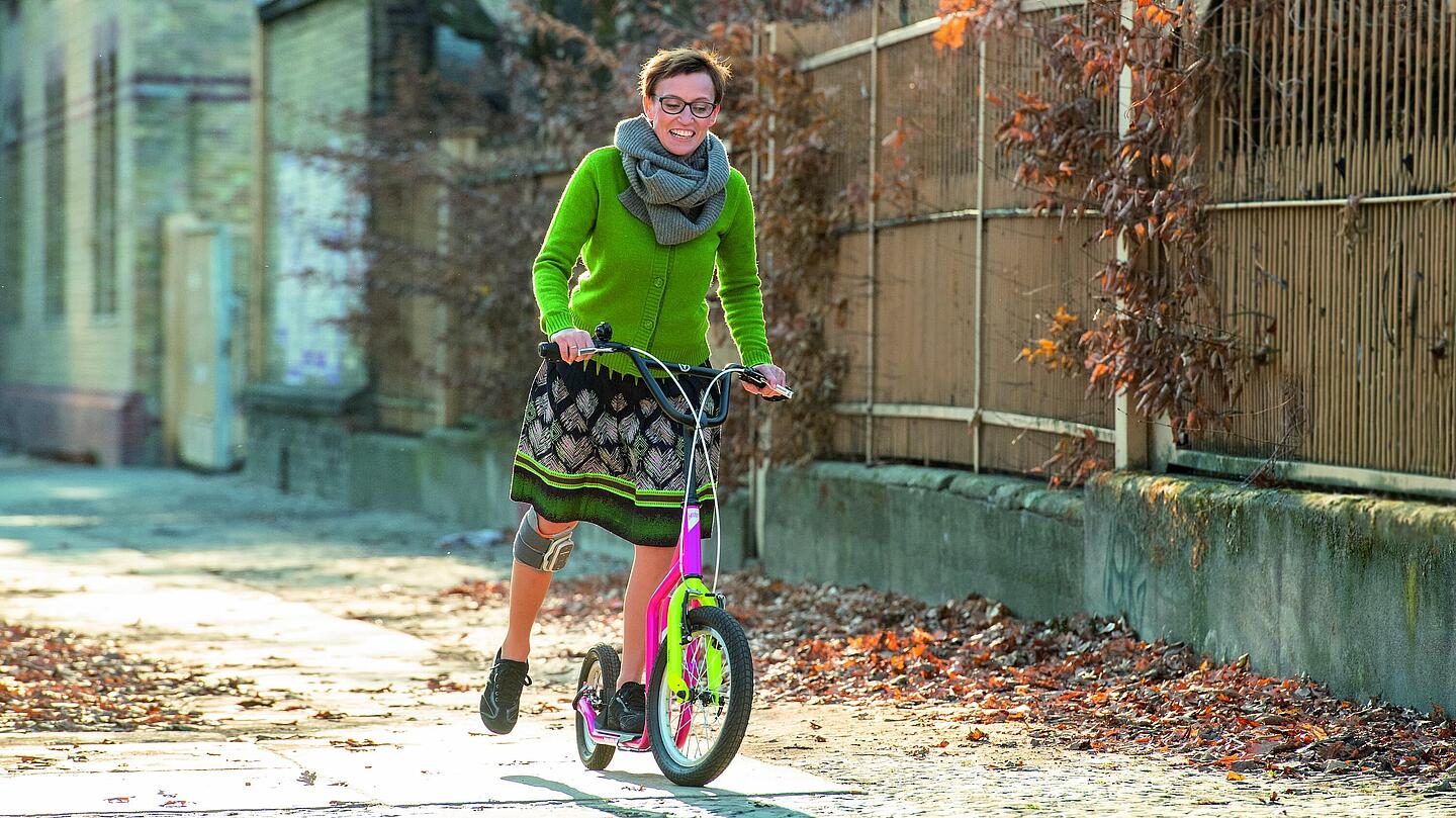 Rollerfahren mit Knie-Manschette, © Ottobock Frau mit Knie-Manschette, die Roller fährt, © Ottobock