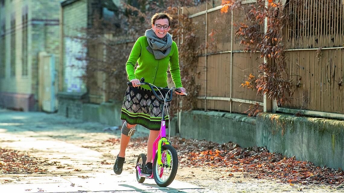 Frau mit Knie-Manschette, die Roller fährt, © Ottobock