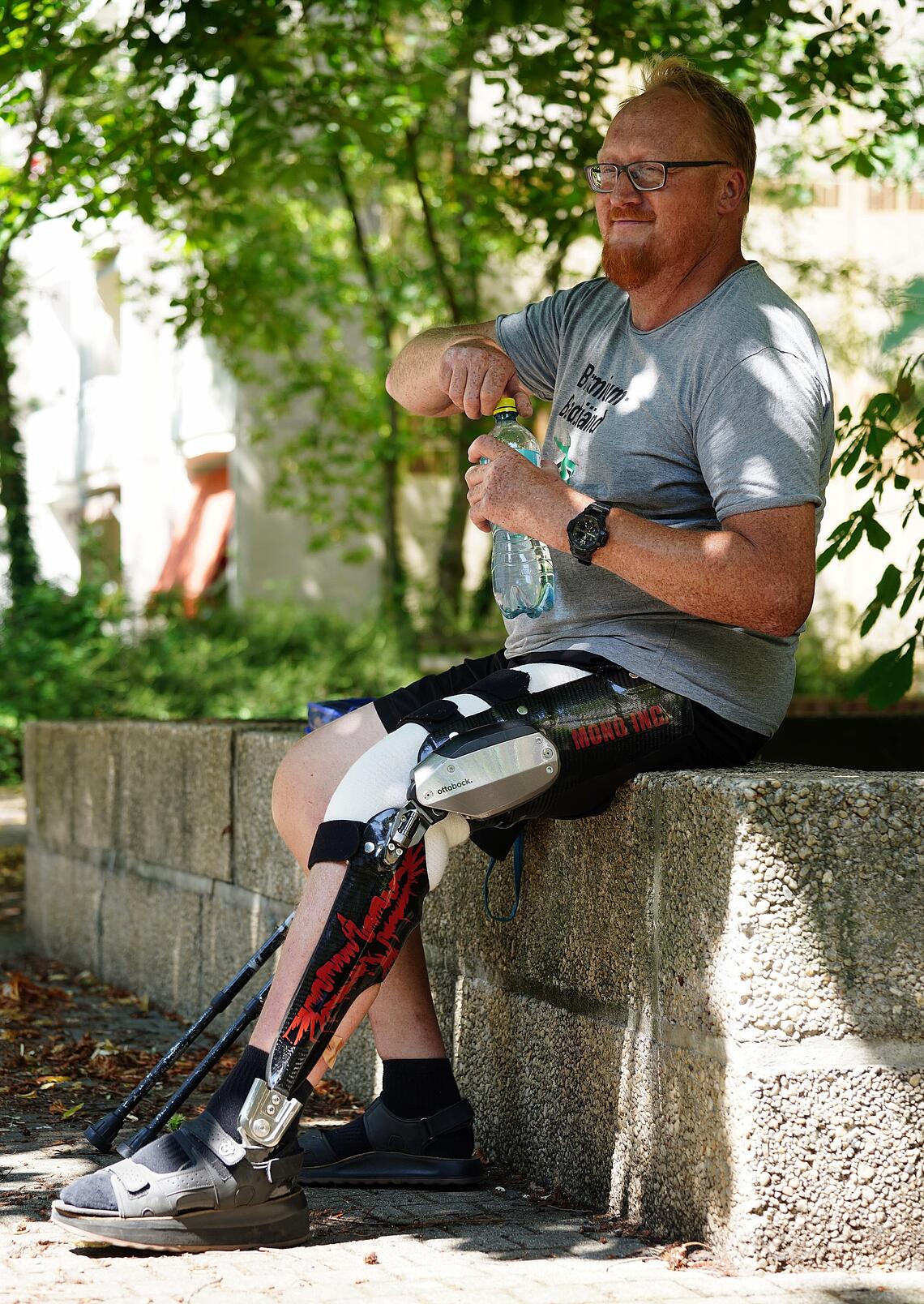 C-Brace-Anwender macht Pause C-Brace-Anwender macht auf einer Steinmauer Pause und trinkt Wasser