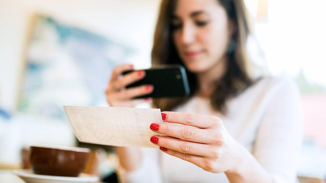 Frau fotografiert Rezept mit Smartphone, ©RyanJLane - iStock