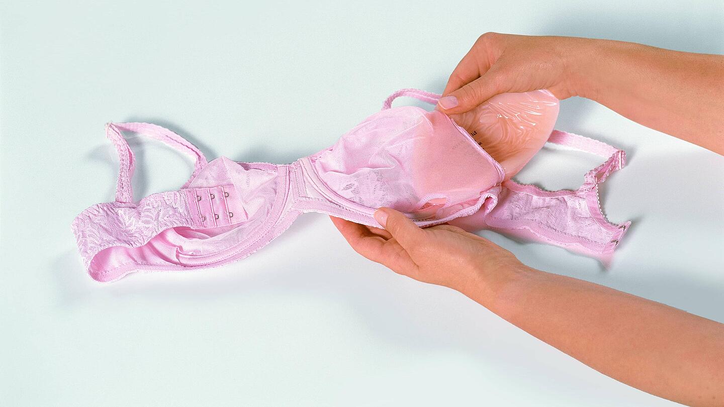 Hand schiebt Epithese in BH | Copyright: Amoena Medizin-Orthopaedie-Technik GmbH