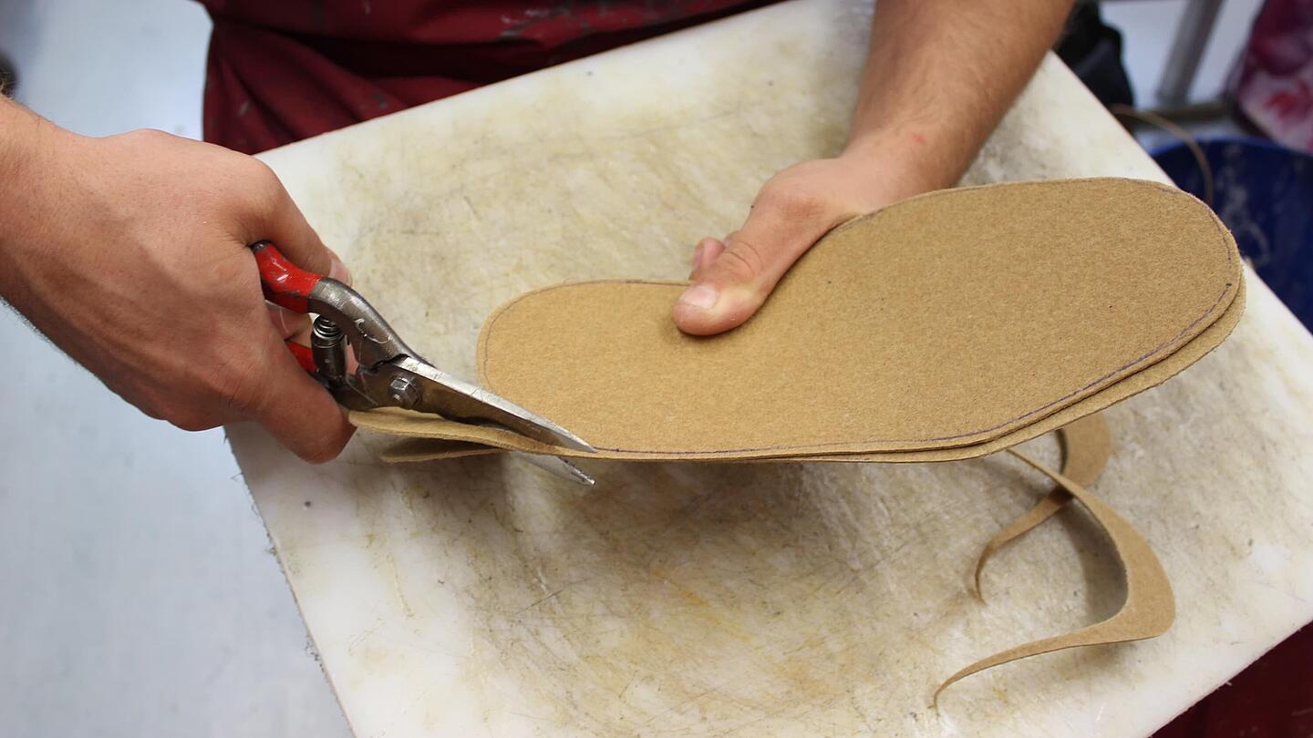 eine Einlage wird im Rahmen der Fertigung in Größe und Form geschnitten