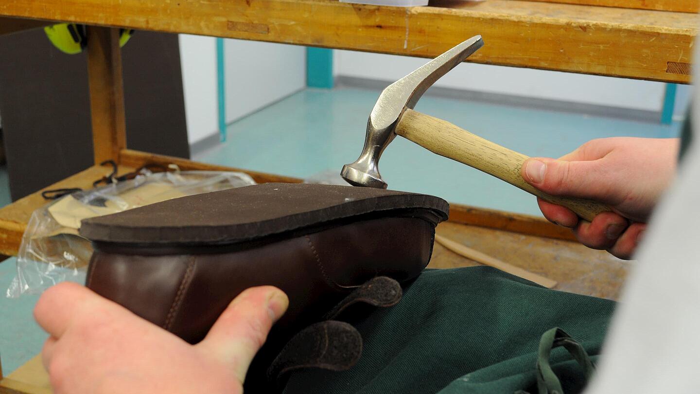 Annageln der Sohle mit dem Hammer die Sohle des Schuhs wird zur Befestigung mit dem Hammer bearbeitet