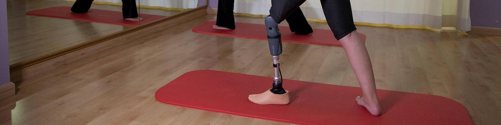 Frau beim Yoga mit Unterschenkelprothese Rheo Knee, © Copyrights by Össur hf.  Frau beim Yoga vor dem Spiegel mit Unterschenkelprothese Rheo Knee, © Copyrights by Össur hf.