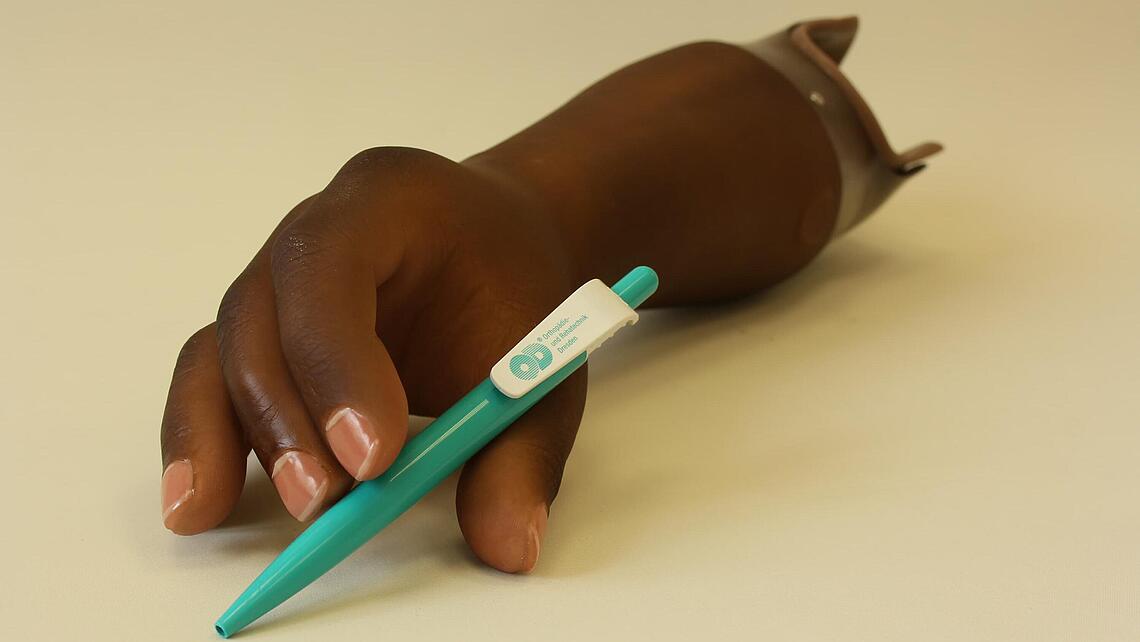 dunkelhäutige myoelektrische Armprothese mit Kugelschreiber