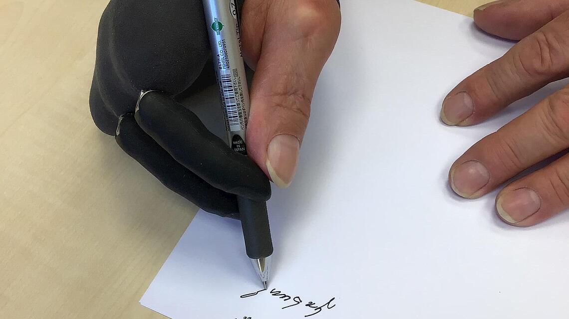 Teilhandprothese, die einen Stift hält und mit der geschrieben wird