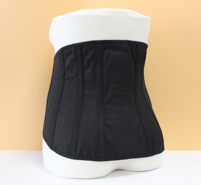 Rückenansicht eines schwarzen Kreuzstützmieders mit Klettverschluss zur Stabilisierung und Haltungsverbesserung durch zirkuläre Kompression